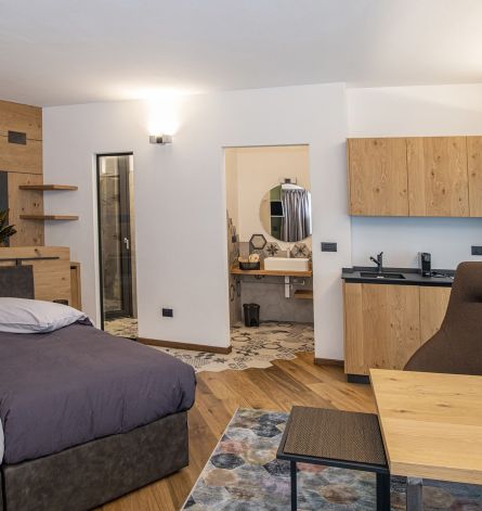 Arredamenti su misura per camera d'albergo: struttura in metallo per guardaroba, tutto legno per angolo cottura, testata letto.